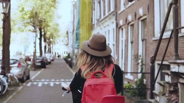 Girl on a bicycle with a red back seat. Slow motion close-up. Happy female tourist. Leisure bike ride along street. - Filmmaterial, Video