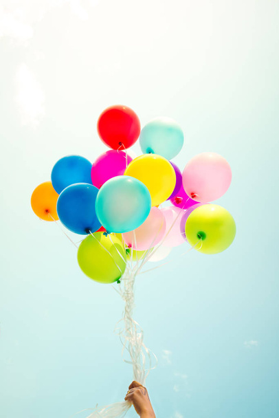 Girl hand holding multicolor balloons done with a retro instagram filter effect, concept of happy birth day in summer and wedding honeymoon party, Vintage color tone style - Valokuva, kuva