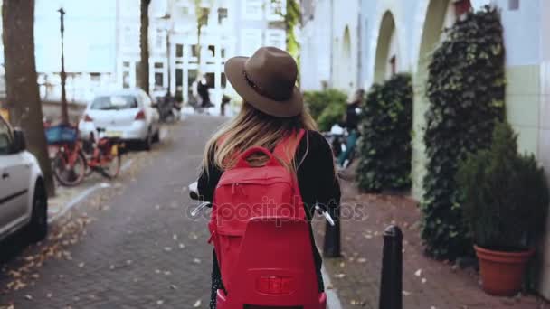 Back view. Student Caucasian girl rides a bicycle. Slow motion. Happy local daily commuter. Lifestyle background shot. - Filmmaterial, Video
