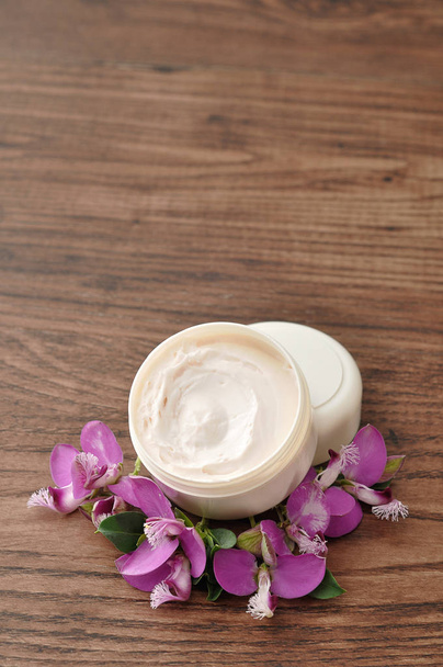 Une baignoire de lotion pour les mains affichée avec de petites fleurs violettes
 - Photo, image