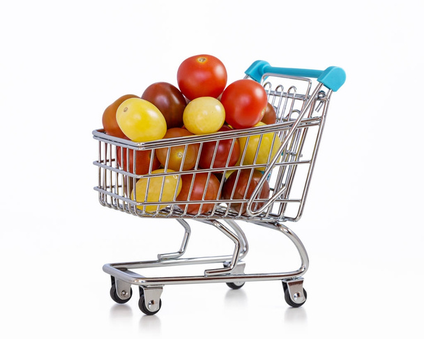 Multicolored cherry tomatoes in miniature shopping trolley isolated on white background. - Fotoğraf, Görsel