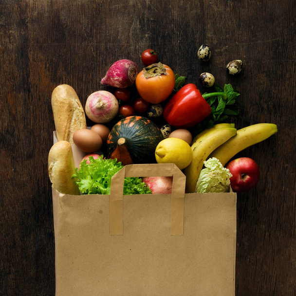 Paper bag of different health food on dark wooden background - Photo, Image