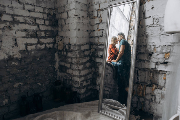 Odbicie w lustrze małżonków, ich siedząc na parapecie. Historia miłości - Zdjęcie, obraz