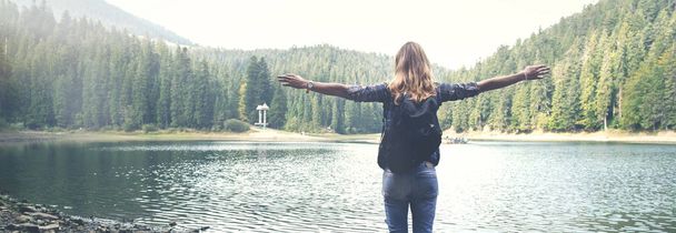 Young girl stands near mountain lake - Fotoğraf, Görsel