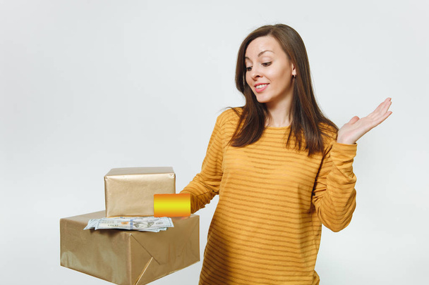 Beautiful caucasian smiling young happy birthday woman in yellow clothes holding credit card, lot of cash money, golden gift boxes with present, celebrating holiday party on white background isolated. - Fotó, kép