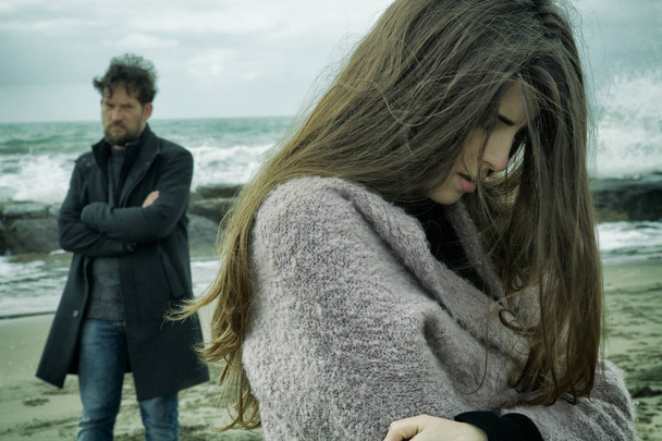 Злий чоловік виглядає сумною дівчиною після бою перед океаном середній шок
 - Фото, зображення