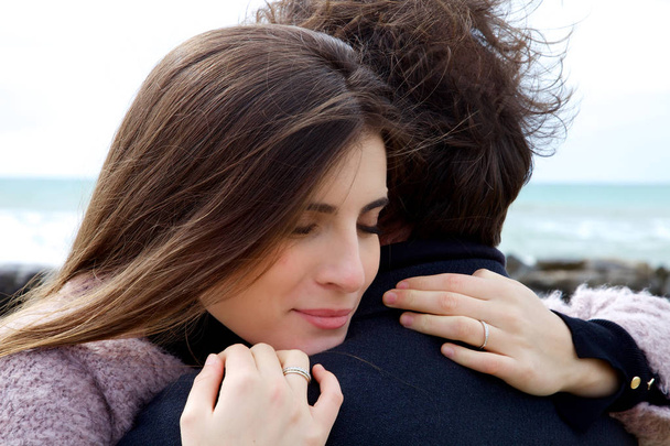 Woman in love hugging strong husband in front of ocean  - Photo, Image