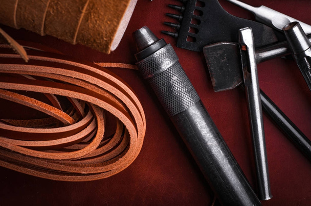 close up of handcraft leather tools set and rolled leather fabric with straps - Fotó, kép