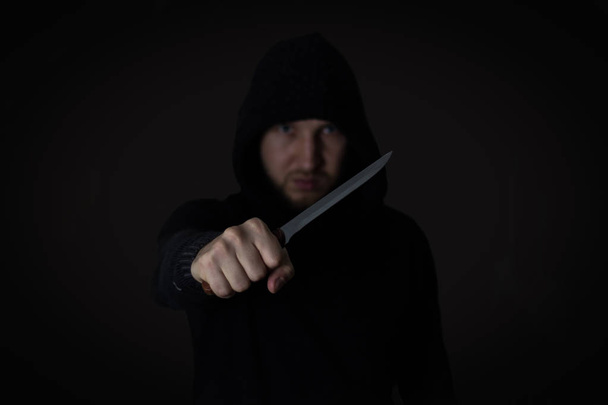 μεγάλο μαχαίρι στο χέρι του νεαρού άνδρα της ένα μαύρο σακάκι σφιγμένη γροθιά. Def - Φωτογραφία, εικόνα