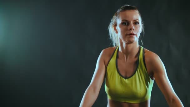Uma jovem mulher atraente em um terno esportivo fortalece os músculos no clube de fitness
 - Filmagem, Vídeo