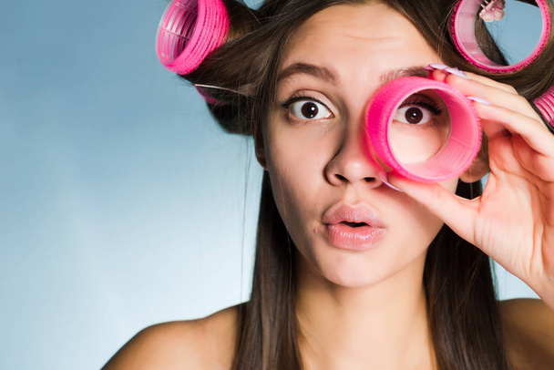 a young girl looks ahead in surprise with curlers - Photo, image