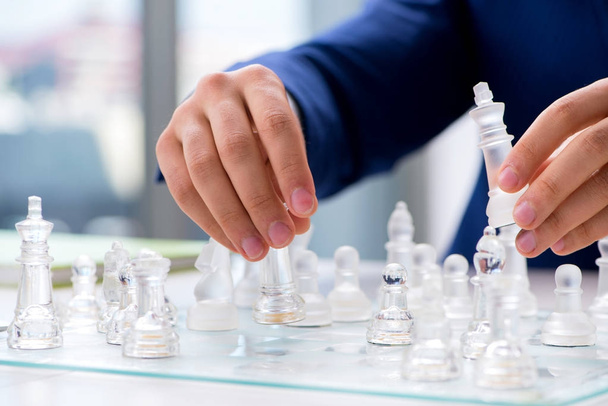 Giovane uomo d'affari che gioca a scacchi di vetro in ufficio - Foto, immagini