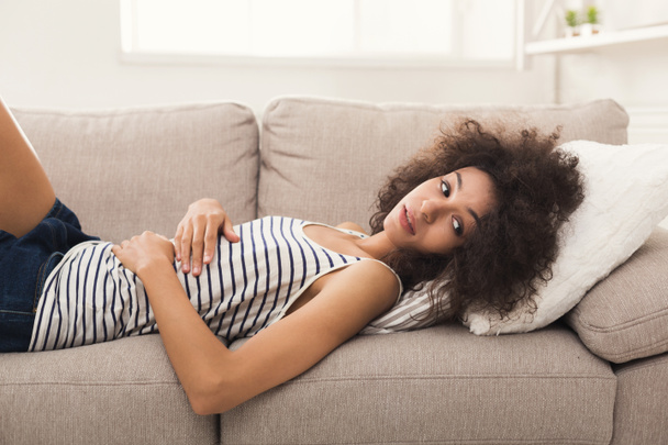 Triste femme afro-américaine sur le canapé à la maison
 - Photo, image