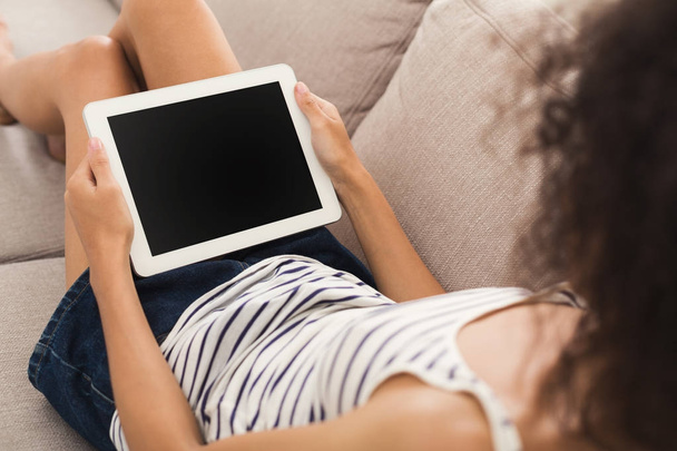 Неузнаваемая девушка с планшетом на диване
 - Фото, изображение