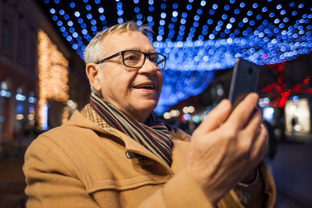 Außenporträt eines glücklichen Seniors, der nachts in der Stadt fotografiert.  - Foto, Bild