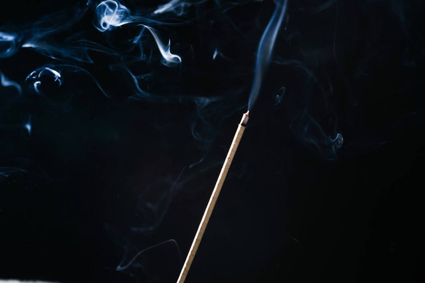 A small smoking stick with incense on a black background - Foto, Bild