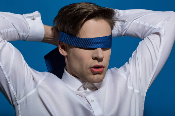 Man blindfolded with necktie on blue background - Fotó, kép