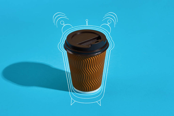 Café caliente en taza de papel marrón con tapa negra sobre fondo azul
 - Foto, Imagen