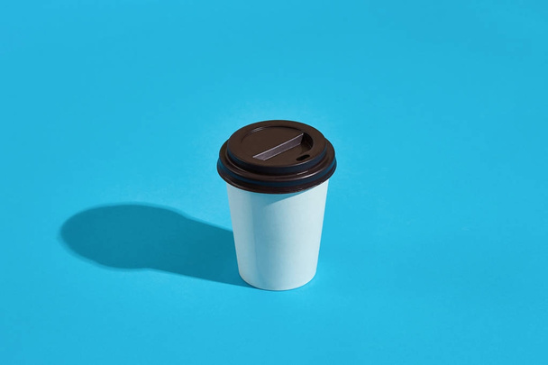 Café quente em copo de papel branco com tampa preta no fundo azul
 - Foto, Imagem