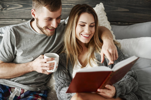 Young couple reading book at bedroom  - Photo, Image