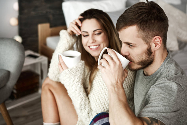 Vidám férfi és nő kávét iszik a hálószobában  - Fotó, kép