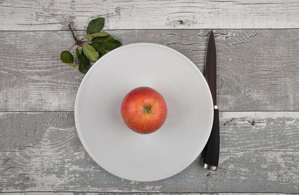 Apple with knife and leaves on weathered wood - Foto, afbeelding
