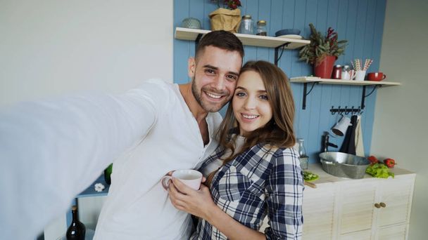 POV of Young happy couple taking selfie photos while having breakfast time in the kitchen at home - Фото, изображение