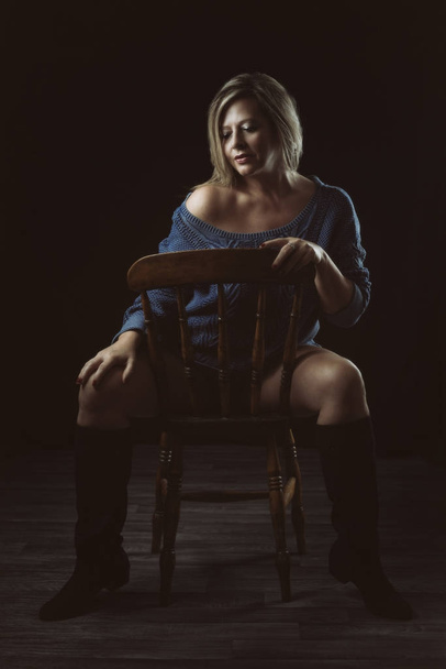Femme mature assise à côté d'une chaise en bois
 - Photo, image