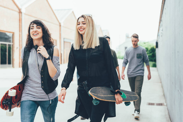 Due donne che tengono skateboard a piedi all'aperto
  - Foto, immagini
