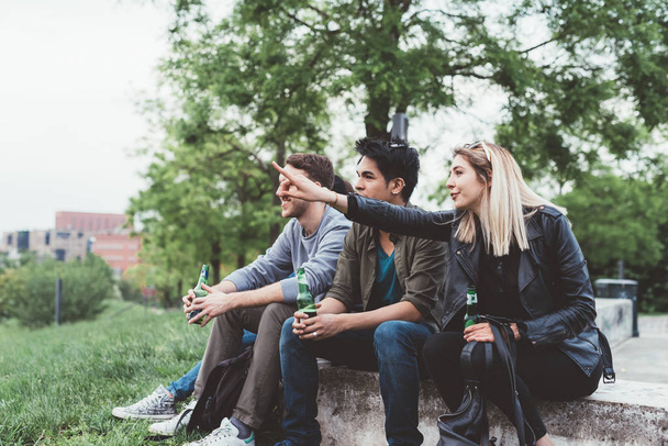 Gruppe von Freunden multiethnisch sitzen im Freien und trinken Bier  - Foto, Bild