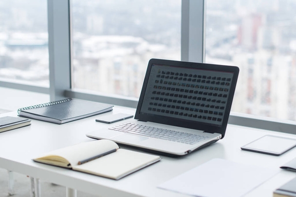 Vista lateral del escritorio de oficina con portátil en blanco y varias herramientas
. - Foto, Imagen