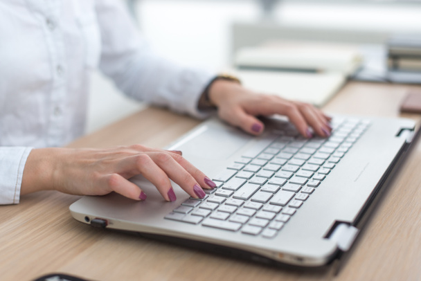 Az üzleti nő kezében laptop számítógépen dolgozik közelről. - Fotó, kép