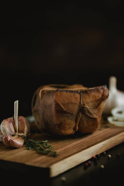 Chunk of salted smoked lard in gauze with a rope.Traditional Russian and Ukrainian meal.Healthy food with spices, herbs, onion and garlic.Food photo for recipe or cookbook. Rustic clolor style - Foto, Imagem