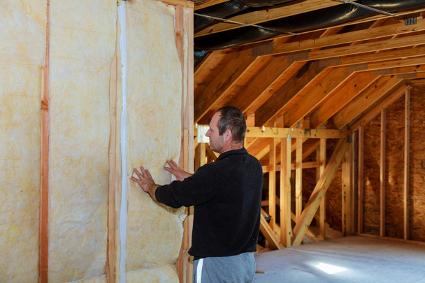 werknemer thermisch isolerende een huis zolder met behulp van minerale wol - Foto, afbeelding