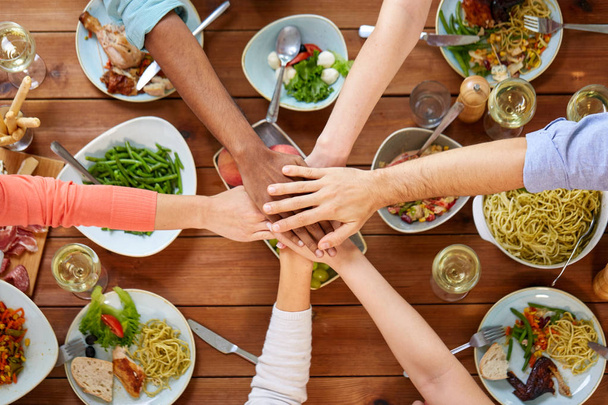 people holding hands together over table with food - Foto, Imagen