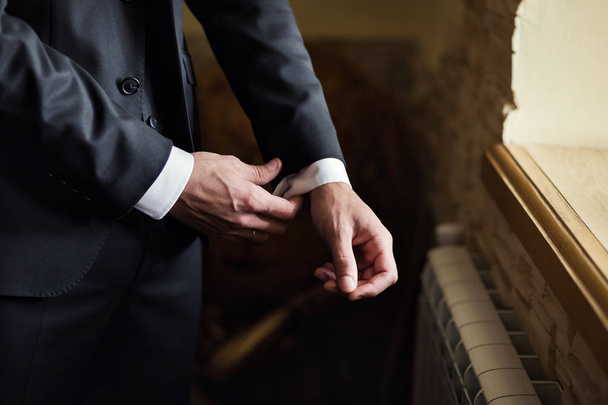 Empresario lleva una chaqueta, manos masculinas primer plano, novio preparándose en la mañana antes de la ceremonia de boda - Foto, Imagen
