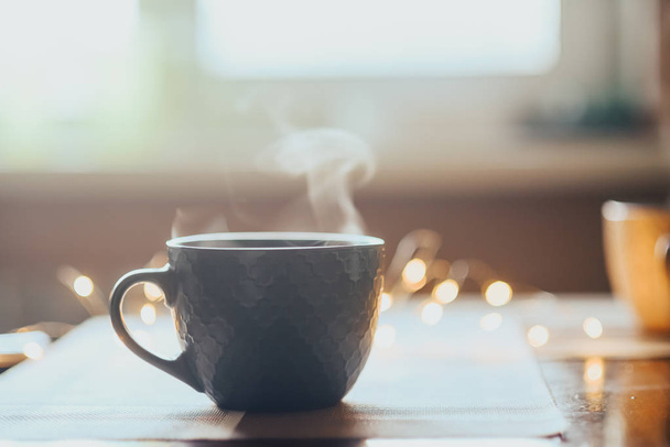Гарячої чашкою чаю або кави. Кубок з пар, що на столі. Тепле світло у фоновому режимі - Фото, зображення