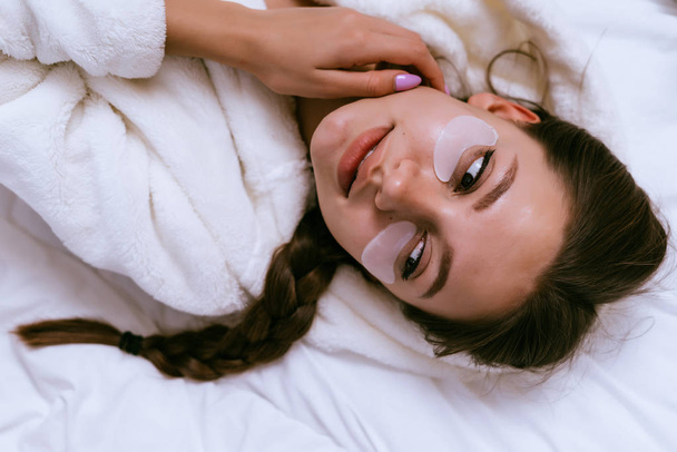 une jolie jeune fille en robe blanche repose sur un lit, sous les yeux d'un patch
 - Photo, image