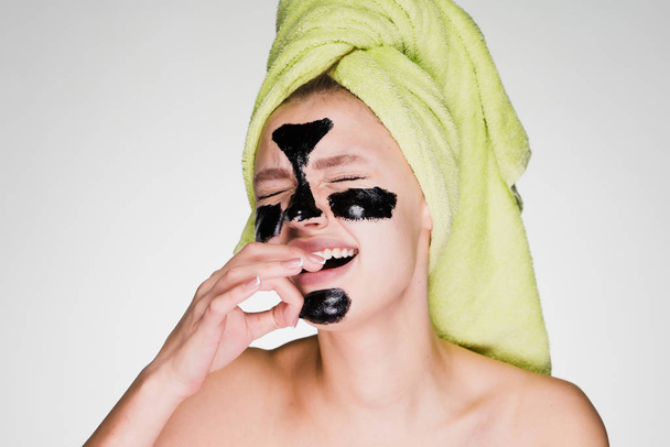 sad young girl with a towel on her head removes a black mask from her face, it hurts - Foto, immagini
