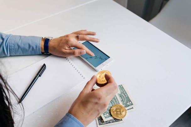 girl financier studies graphics kryptovalyut, holds in his hand a gold bitcoin - Photo, Image
