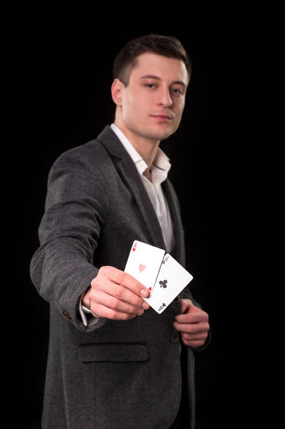 Kaukázusi fiatalember visel öltöny kezében két ászt a kezében, a fekete háttér. Szerencsejáték-koncepció. Kaszinó - Fotó, kép