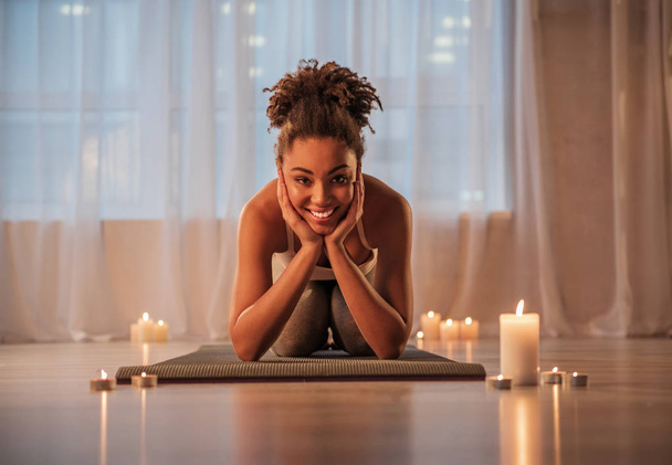 Cheerful young woman doing yoga in cozy atmosphere - Fotó, kép