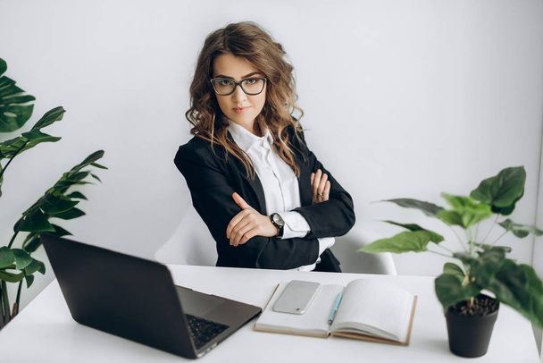 Atrakcyjny biznes kobieta siedzi przy biurku w jej miejscu pracy, laptop, telefon komórkowy i notebooków - Zdjęcie, obraz
