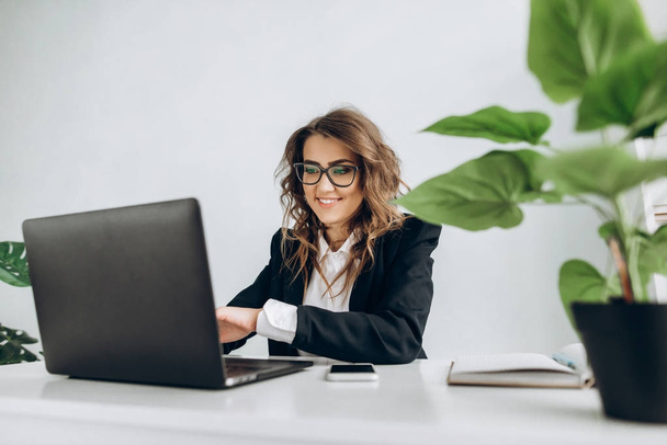 attraktive Geschäftsfrau lächelt während eines Arbeitsprozesses an ihrem Arbeitsplatz im Büro - Foto, Bild