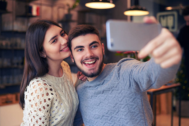 Homme joyeux faisant selfie avec sa petite amie au café
 - Photo, image