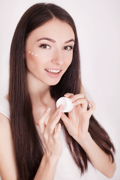 目の前で化粧品のクリームを適用する健全な顔を持つ女性 - 写真・画像