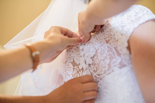 Maman aide la mariée à habiller une robe de mariée blanche et belle
 - Photo, image