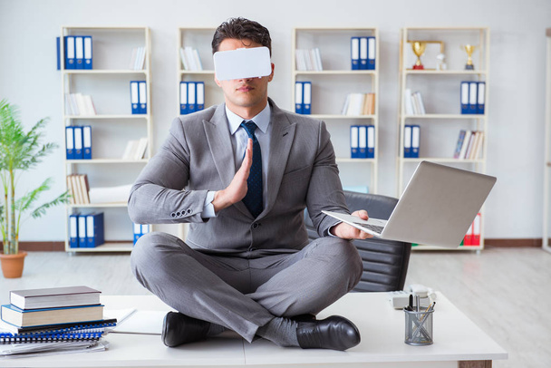 Zakenman in virtual reality VR bril mediteren op bureau top - Foto, afbeelding