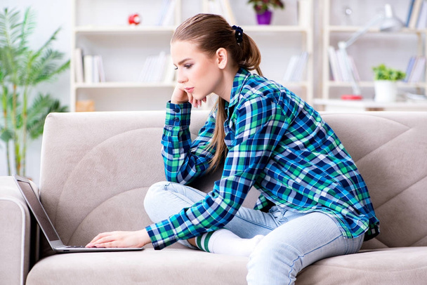Female student sitting on the sofa with laptop - 写真・画像