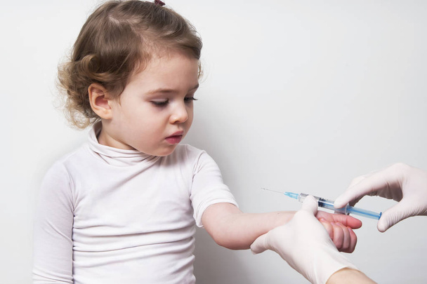 Médico de la mano con jeringa vacunación del bebé niña vacuna inyectable contra la gripe
 - Foto, imagen